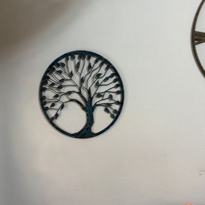 Circular metal tree of life wall art with a distressed blue-green finish.