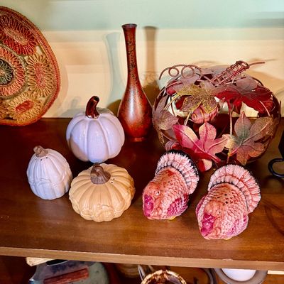 Sale Photo Thumbnail #107: Collection of Thanksgiving and autumn-themed decor, including ceramic turkey salt and pepper shakers, ceramic pumpkins, a metal leaf pumpkin, and a slender red vase.
