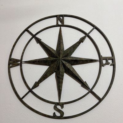 Sale Photo Thumbnail #169: Large metal compass rose wall decor with a distressed, dark bronze finish.