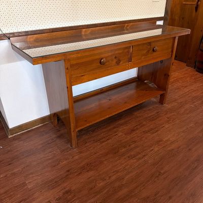 Rustic pine console table featuring a glass-protected top, two drawers with wooden knobs, and a lower display shelf.
