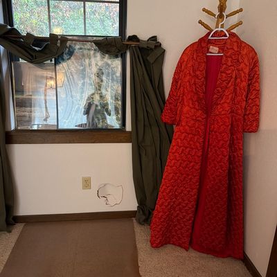 Sale Photo Thumbnail #202: Vintage mid-century red quilted satin robe hanging on a wooden coat rack next to a window.