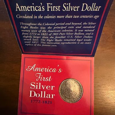 Sale Photo Thumbnail #233: America's First Silver Dollar replica coin, modeled after the Spanish Eight Reales minted between 1772 and 1821, presented in its original informational display folder.