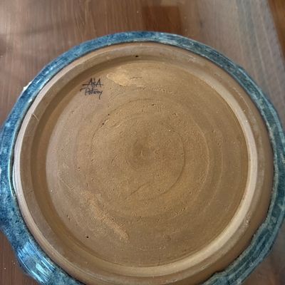 Underside of a studio art pottery piece showing the unglazed clay bottom and the signature "A&A Pottery".