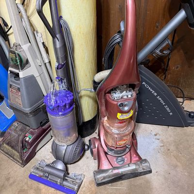 Sale Photo Thumbnail #278: Selection of floor cleaning equipment, including a purple Dyson Ball upright vacuum, a metallic red Bissell Momentum upright vacuum, and a Hoover SteamVac Ultra carpet cleaner.