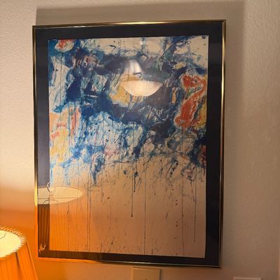 Sale Photo Thumbnail #103: Framed abstract expressionist print featuring blue, orange, and yellow paint splatters and drips, presented in a gold-toned metal frame with a dark blue mat.