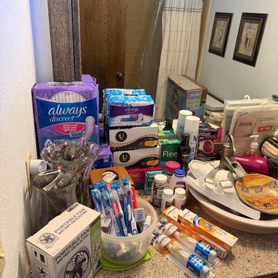 Assorted personal care and hygiene items, including toothbrushes, Always feminine products, a portable fan, and various toiletries...