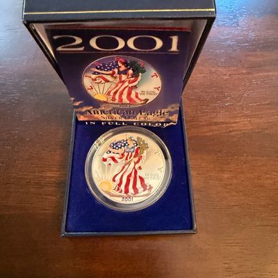 Sale Photo Thumbnail #229: 2001 American Eagle Silver Dollar in full color, housed in its original blue velvet-lined presentation box with certificate of authenticity.