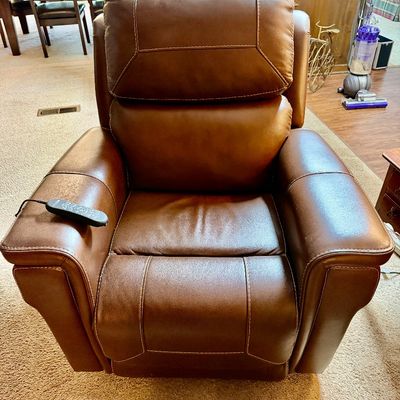 Sale Photo Thumbnail #106: Contemporary brown leather power recliner with contrast stitching and a wired remote control, showing light wear.