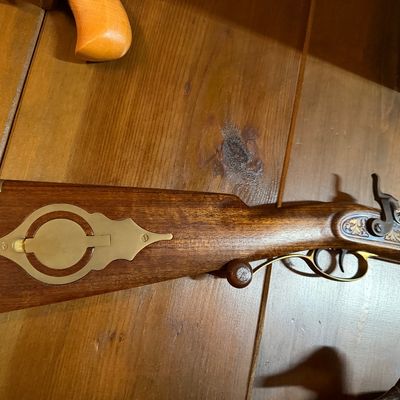 Vintage percussion cap muzzleloader rifle featuring a wooden stock with brass patch box and hardware, showing ornate engraving on the...