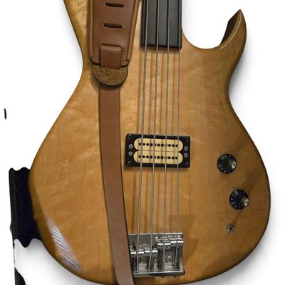 Fretless electric bass guitar featuring a natural wood finish, dark fingerboard, humbucker pickup, and an attached brown leather strap.