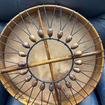 Remo frame drum featuring a wooden crossbar handle and an adjustable tuning system with wooden beads and tension cords.