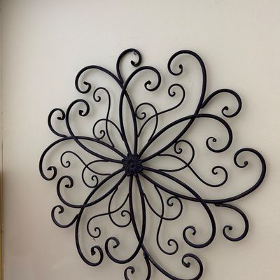 Sale Photo Thumbnail #174: Large circular wrought iron wall art featuring a symmetrical scrollwork design with a central floral medallion.