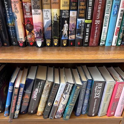 Sale Photo Thumbnail #180: Two shelves of fantasy and sci-fi hardcover and paperback books, featuring titles by Terry Goodkind, Neil Gaiman, and David Eddings.