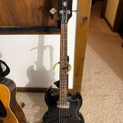 Epiphone SG-style electric bass guitar in black finish, displayed on a stand.