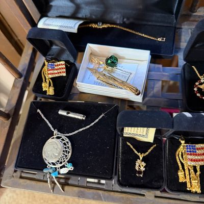 Sale Photo Thumbnail #133: Collection of fine and costume jewelry in display boxes, including a silver-tone coin pendant necklace, American flag pins, and gold-tone chain necklaces.