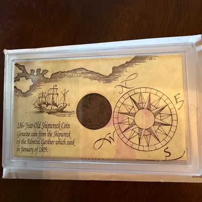 Sale Photo Thumbnail #251: Genuine shipwreck coin from the Admiral Gardner, which sank in January of 1809, presented in a protective plastic display case with illustrated historical backing.