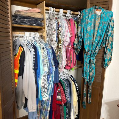 Sale Photo Thumbnail #195: A closet filled with various men's and women's clothing, featuring a teal and gold patterned robe hanging on the door.