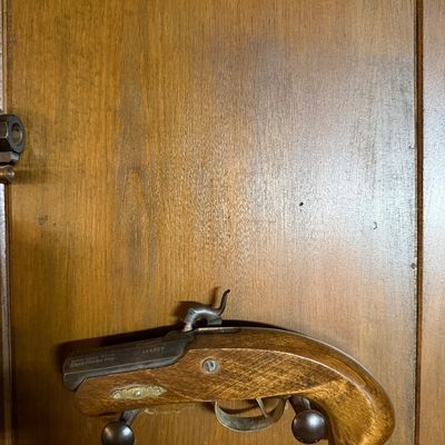Dikar Spain .45 caliber black powder percussion pistol with a wooden stock, mounted on a wooden wall display.