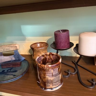 Sale Photo Thumbnail #127: Collection of decorative items including a ulu-style herb chopper with antler handle, glazed studio pottery pieces, and pair of wrought iron candle stands with pillar candles.