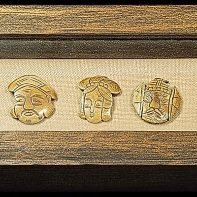 A Set of Seven Japanese Carved Bone Shichifukujin Mask Plaques in a Shadowbox Frame