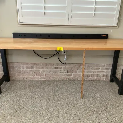 Sale Photo Thumbnail #2: Gladiator brand workbench featuring a thick butcher block wood top, sturdy black metal legs, and an integrated multi-outlet power strip.
