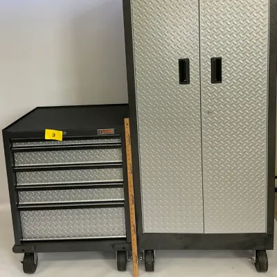 Sale Photo Thumbnail #3: Gladiator brand rolling garage storage set, including a tall two-door cabinet and a matching five-drawer tool chest, both featuring silver diamond-plate door and drawer fronts.