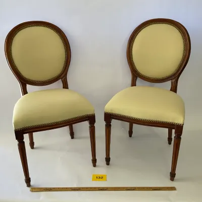 Sale Photo Thumbnail #25: Pair of Louis XVI style side chairs featuring oval backs, pale yellow upholstery with brass nailhead trim, and fluted legs.