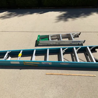 Sale Photo Thumbnail #7: Two Werner ladders, including a blue fiberglass extension ladder and a smaller aluminum step ladder, displayed on a concrete driveway.