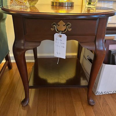 Sale Photo Thumbnail #3: Queen Anne style solid wood end table featuring a single drawer with a brass batwing pull, cabriole legs, and a lower display shelf.