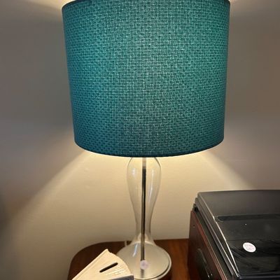 Sale Photo Thumbnail #43: Contemporary table lamp featuring a clear glass hourglass-shaped base and a textured teal fabric drum shade.