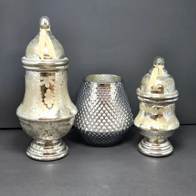 Sale Photo Thumbnail #59: Set of three mercury glass vessels, including two lidded apothecary jars with tied ribbon details and a central diamond-textured vase.