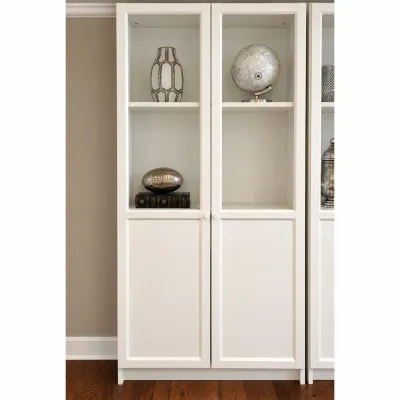 Sale Photo Thumbnail #80: Tall white modern bookcase cabinet with upper glass-front doors, lower solid panel doors, and interior display items including a globe and vase.