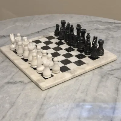 Sale Photo Thumbnail #48: Polished marble chess set featuring hand-carved black and white playing pieces and a matching inlaid board.