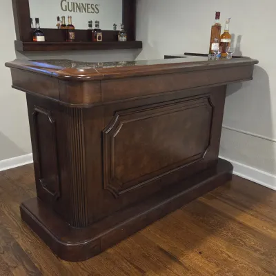 Sale Photo Thumbnail #68: Traditional dark wood home bar featuring a granite top surface and raised panel details, set against a wall with a matching Guinness mirror and shelf.