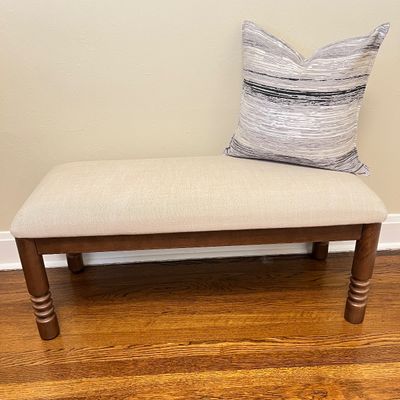 Sale Photo Thumbnail #100: Upholstered bench with dark stain wooden turned legs, paired with a modern striped throw pillow.