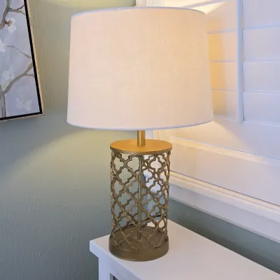 Sale Photo Thumbnail #25: Modern brass table lamp featuring a openwork quatrefoil-patterned base and a neutral fabric drum shade.