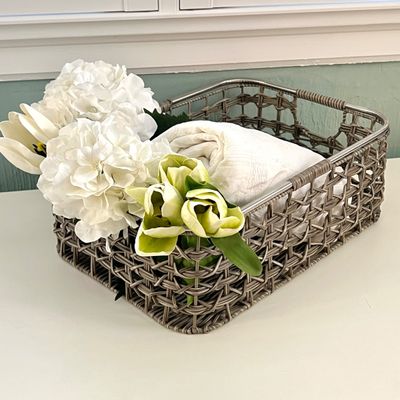 Sale Photo Thumbnail #138: Woven gray wire storage basket filled with white linens and faux white and light green flowers.