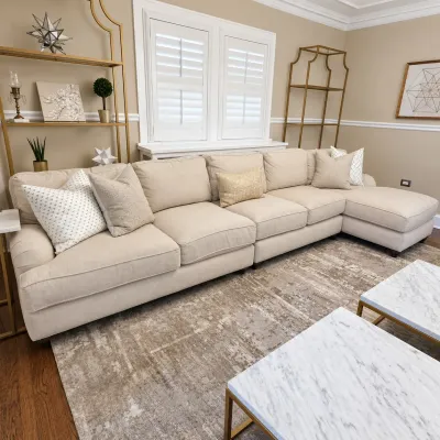 Sale Photo Thumbnail #109: Large beige fabric sectional sofa with chaise and accent pillows, presented alongside brass etageres and marble-top coffee tables.