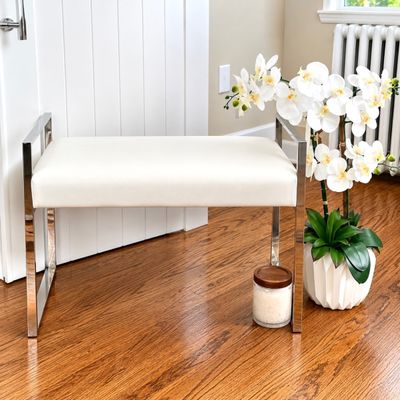 Sale Photo Thumbnail #133: Modern chrome-frame bench with off-white upholstered seat, displayed alongside a potted faux orchid arrangement.