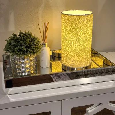 Sale Photo Thumbnail #43: Modern cylindrical table lamp with a patterned mesh shade, displayed alongside decorative home accessories on a mirrored tray.