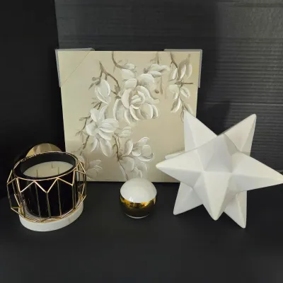 Sale Photo Thumbnail #121: Contemporary home decor collection including a white ceramic starburst sculpture, floral canvas wall art, a three-wick candle in a geometric wire frame, and a white and gold orb accent.