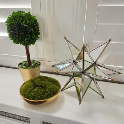 Sale Photo Thumbnail #125: Decorative tabletop accents including a Morrocan-style mirrored star sculpture, a faux boxwood topiary in a gold pot, and a moss-filled gold dish.
