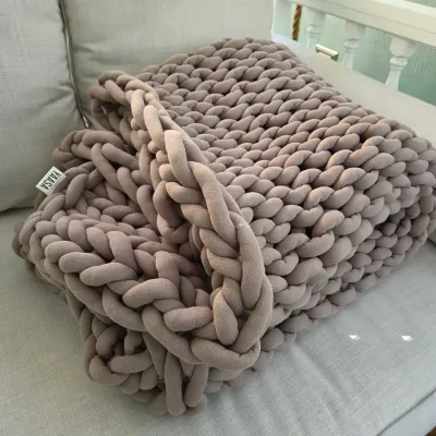Sale Photo Thumbnail #33: Yaasa weighted chunky knit throw blanket in taupe, resting on an outdoor sofa.