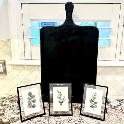 Sale Photo Thumbnail #136: Crate & Barrel Large black wooden paddle-style cutting board, paired with a set of three modern black framed botanical leaf prints.