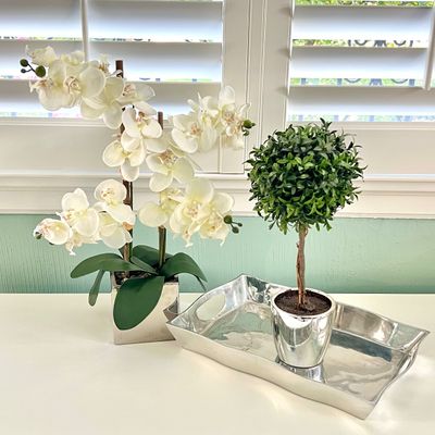 Sale Photo Thumbnail #91: Pair of faux potted plants including a white Phalaenopsis orchid and a topiary ball, displayed alongside a polished silver-tone serving tray.
