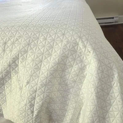 Sale Photo Thumbnail #110: White quilted bedspread featuring a repeating geometric diamond and triangle stitched pattern.