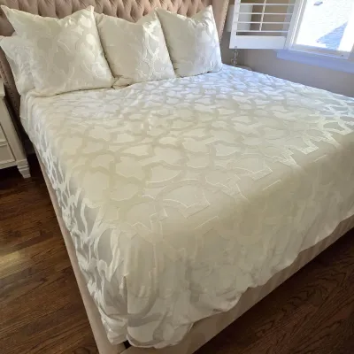 Sale Photo Thumbnail #74: Cream-colored jacquard bedding set with matching decorative pillows, displayed on a fully upholstered bed with a tufted headboard.