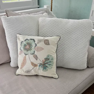 Sale Photo Thumbnail #30: Set of decorative throw pillows, including a floral embroidered accent pillow and two white textured waffle-knit square cushions on a sofa.