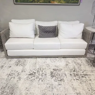 Sale Photo Thumbnail #56: Contemporary grey woven wicker outdoor sofa featuring thick white cushions and a decorative grey accent pillow.