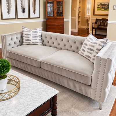 Sale Photo Thumbnail #7: Contemporary tufted light grey velvet sofa with nailhead trim and patterned throw pillows.